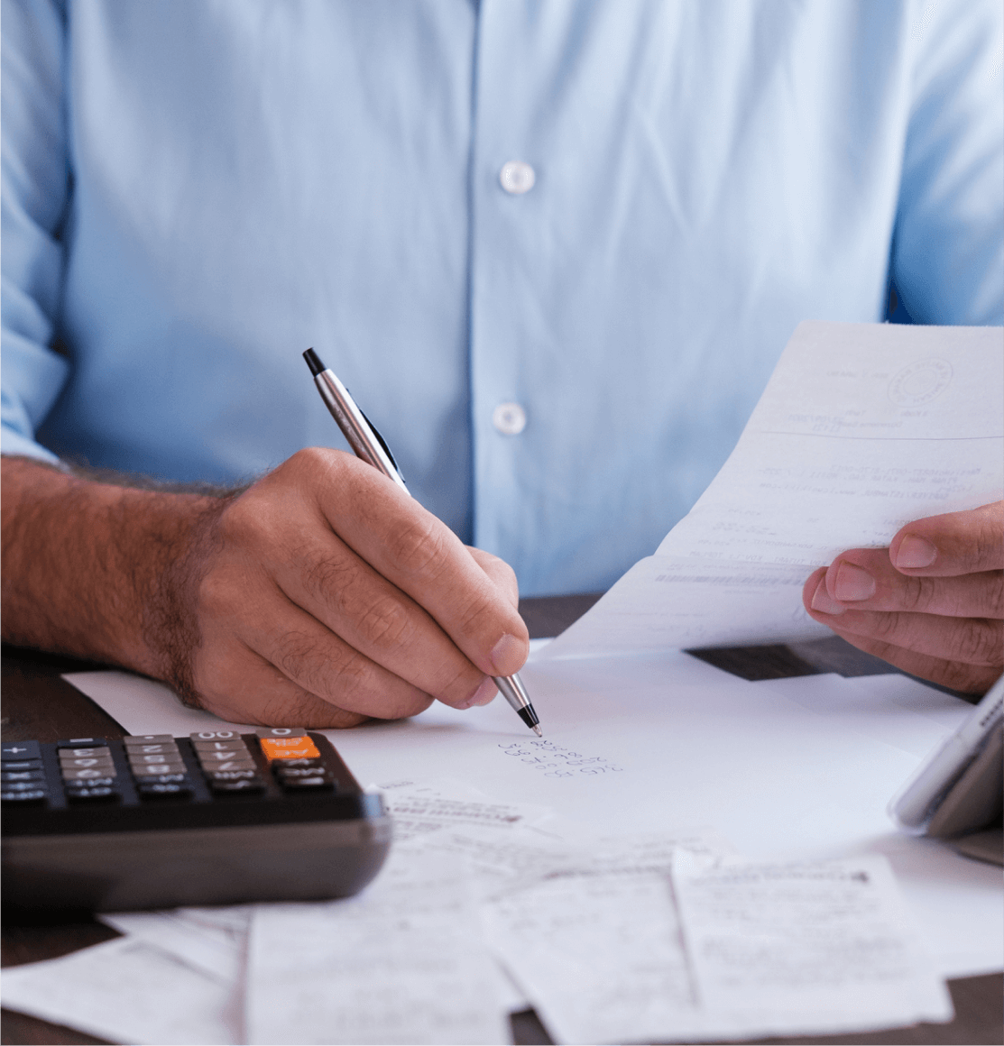 A businessman working with invoices and bills using a calculator illustrates invoice financing.