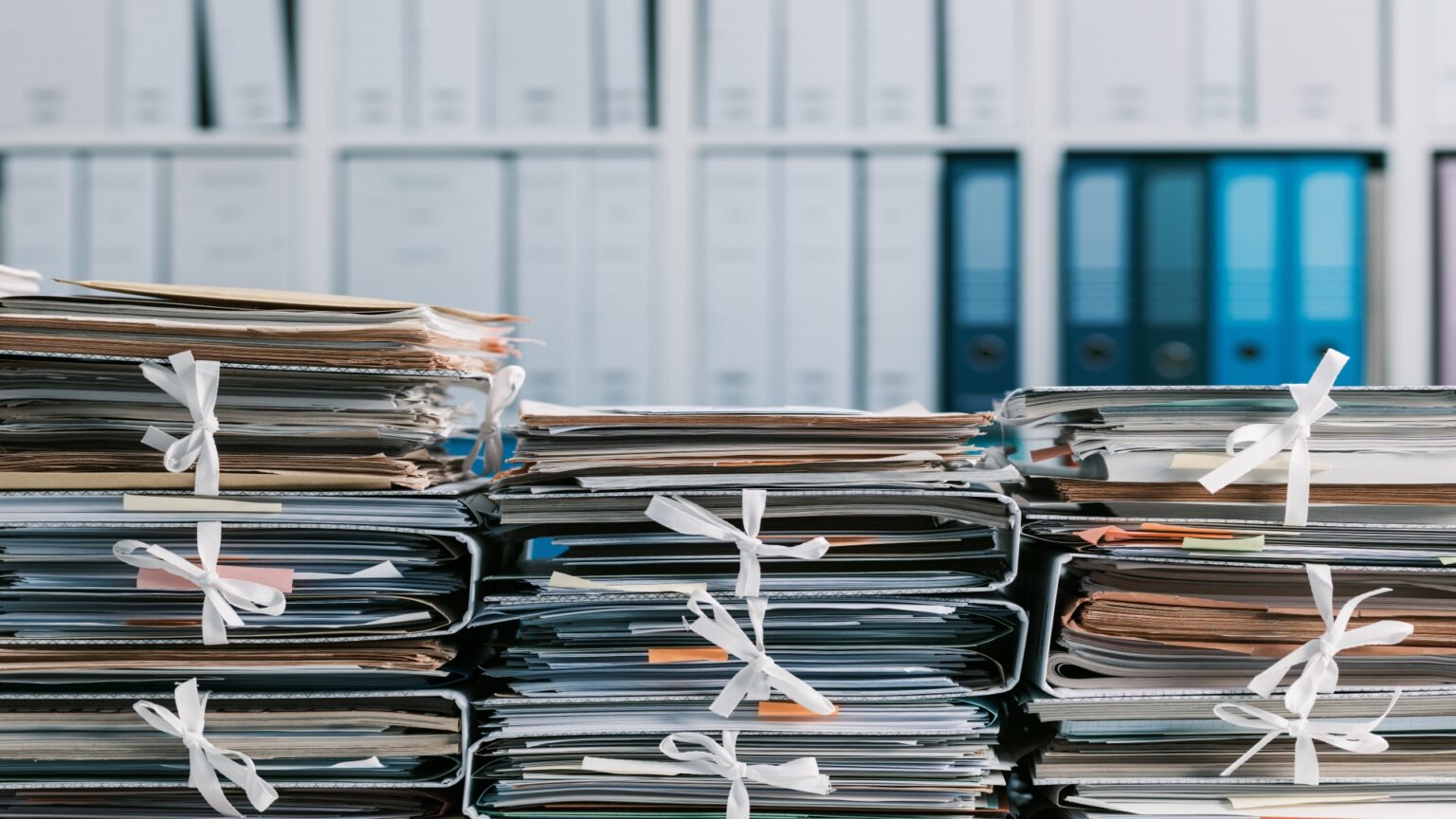 Image of piled-up folders with paper documents.